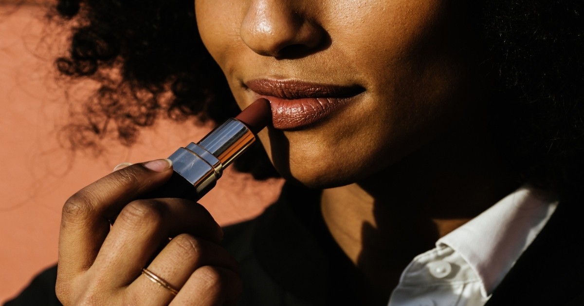 woman putting on lipstick