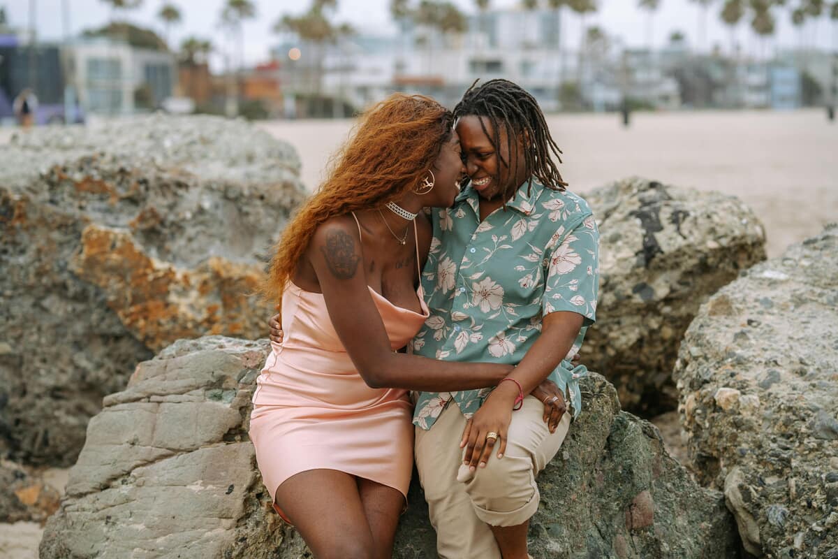 A couple enjoys the beach. Photo by RDNE Stock project from Pexels: https://www.pexels.com/photo/couple-looking-at-each-other-while-sitting-on-boulders-4918849/