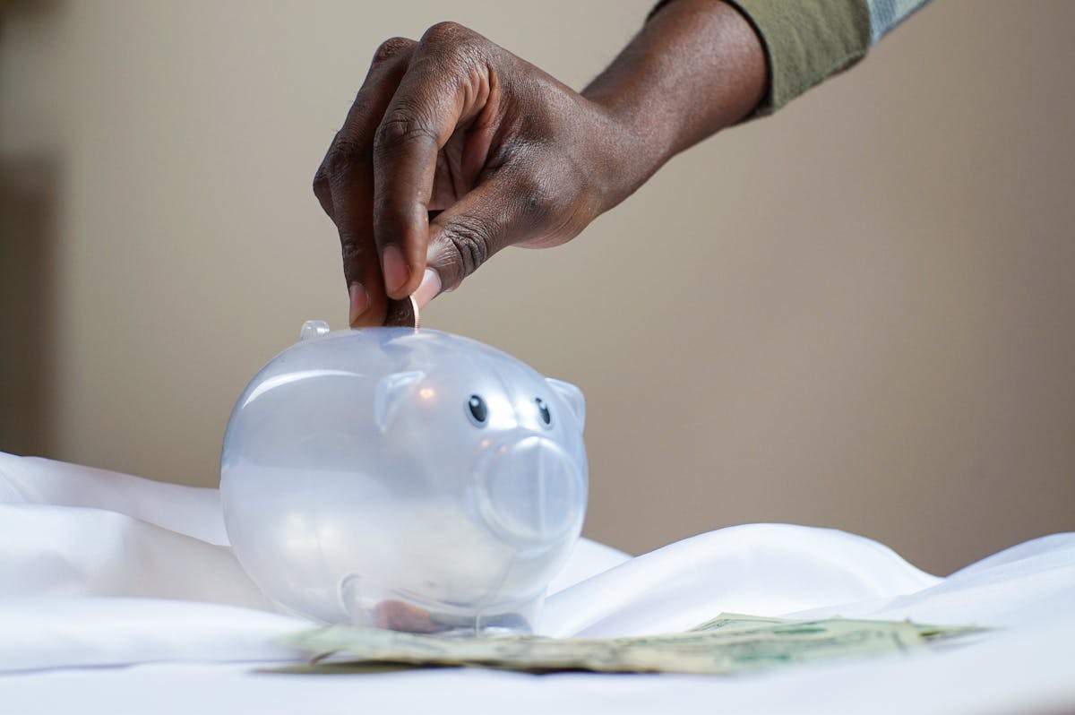 A person puts money in their piggy bank. Photo by Joslyn Pickens: https://www.pexels.com/photo/person-putting-coin-in-a-piggy-bank-3833052/