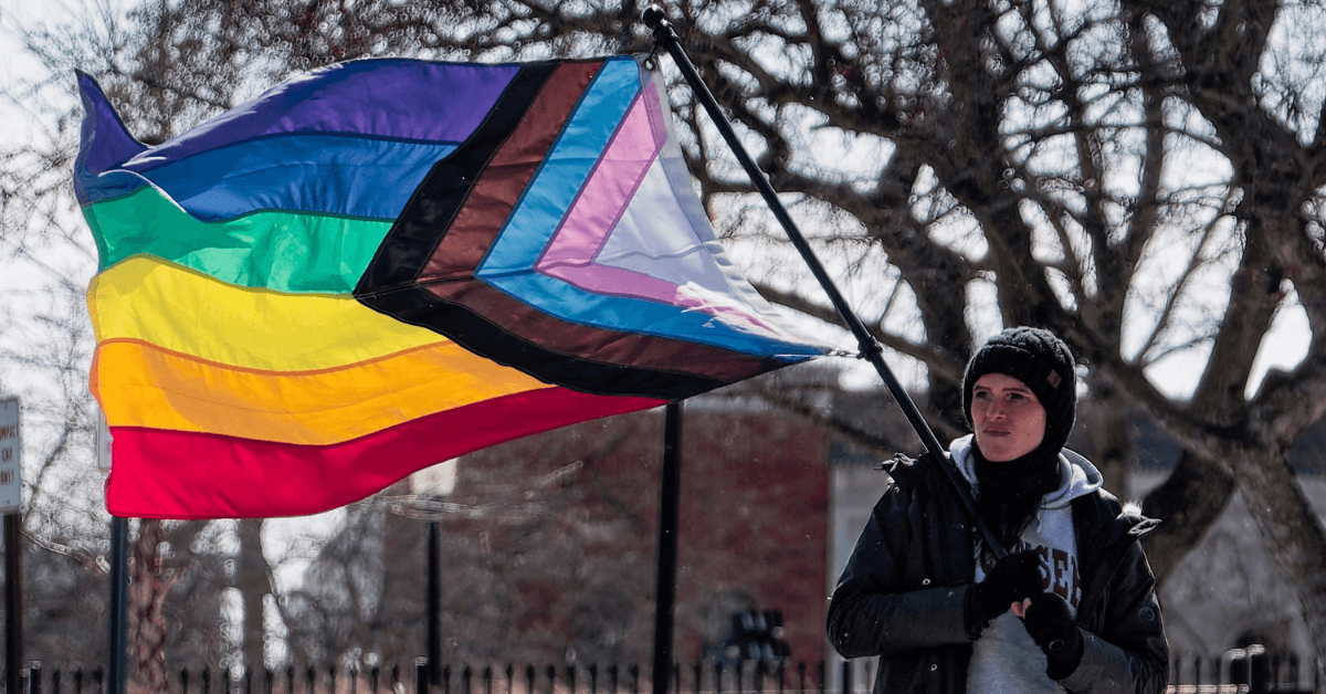 A protester holds a Progress Pride flag during the demonstration.