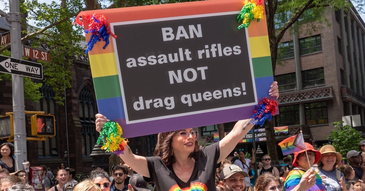 A person holding a sign that reads "BAN assault rifles NOT drag queens!"