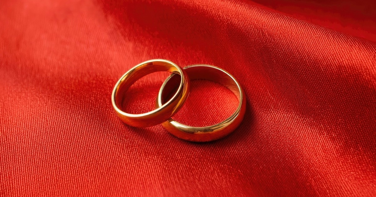 Two wedding rings on a red cloth.