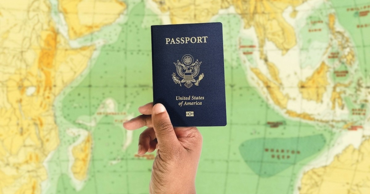 A hand holding a passport over a map.