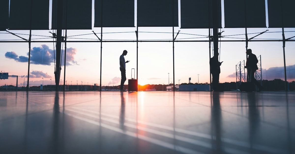 A person standing next to a suitcase in an airport.