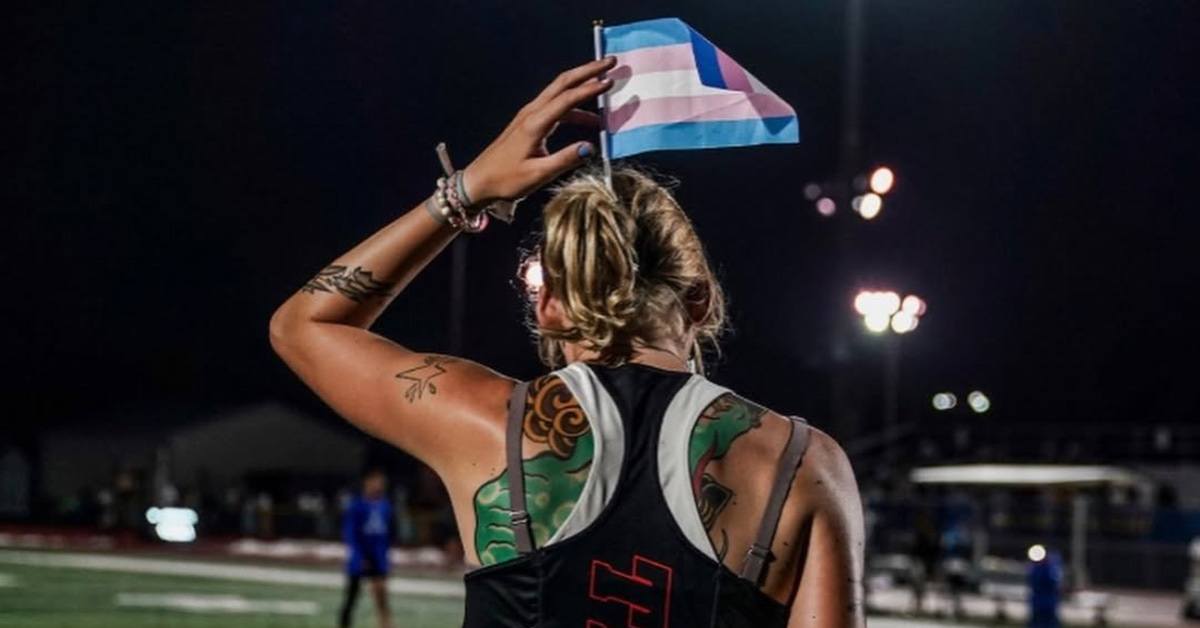 Rear view of Sadie Schreiner at a track event displaying a trans pride flag in her hair