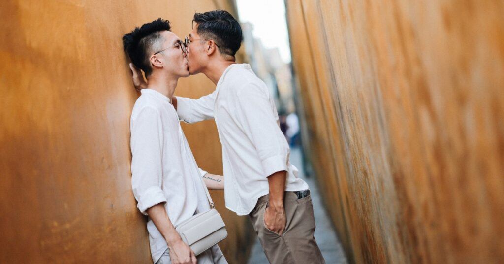 two men kiss in small hallway