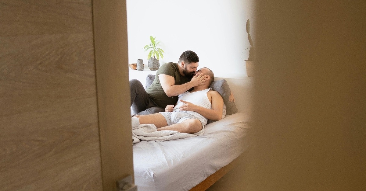 Gay male couple in bed kissing