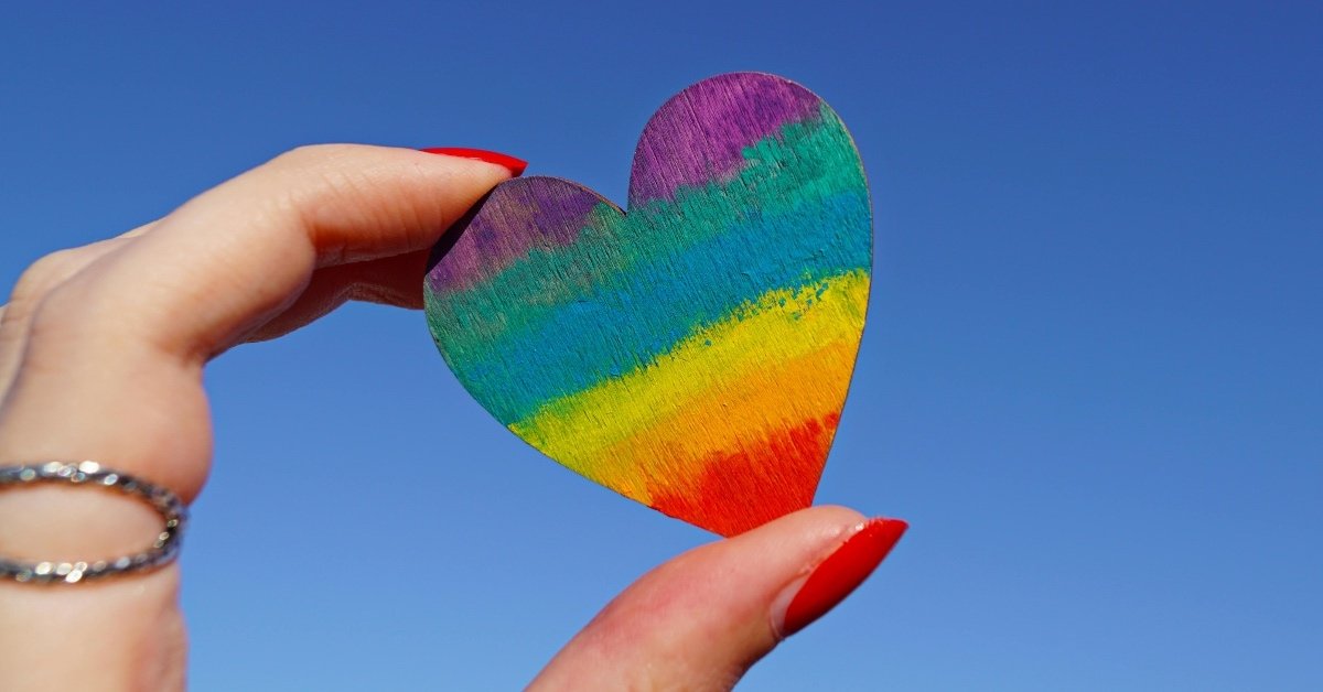 rainbow heart held between two fingers