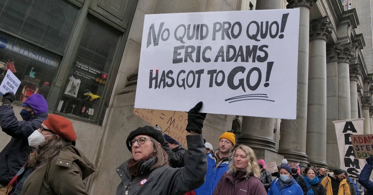 A person with a sign that reads "No Quid Pro Quo! Eric Adams Has Got To Go!"