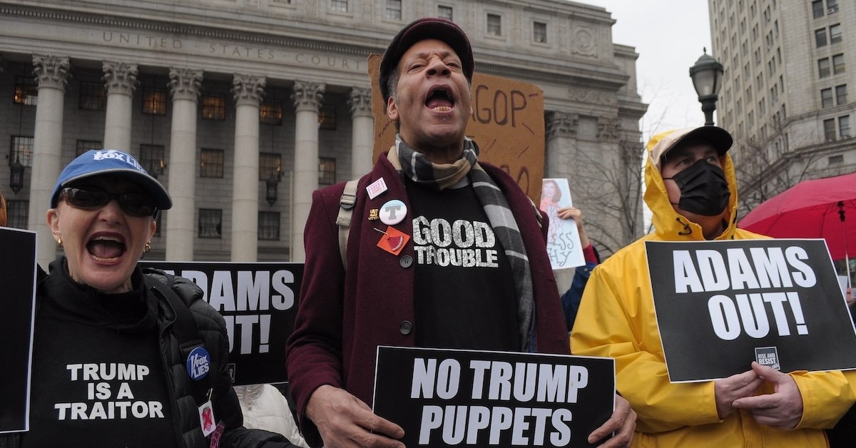 Protestors with signs that read "Adams Out" and "No Trump Puppets."