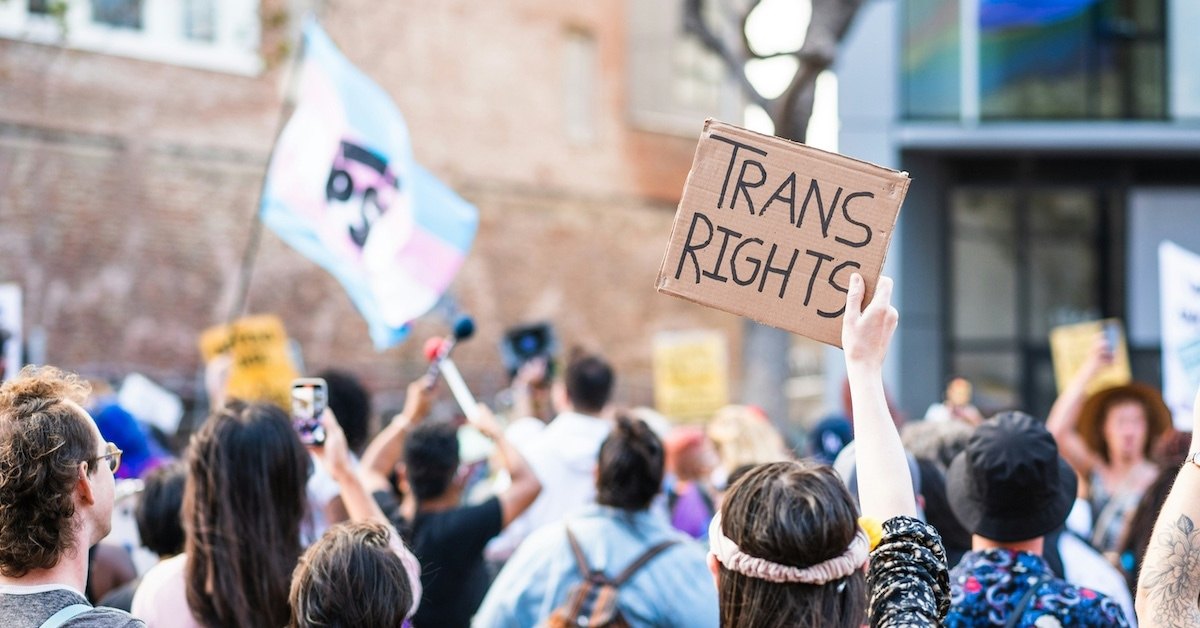 A person holding up a sign that reads "TRANS RIGHTS."