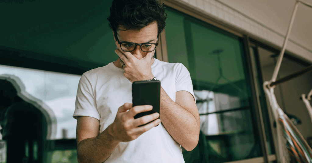 Man Looking at Phone with Hand on Face