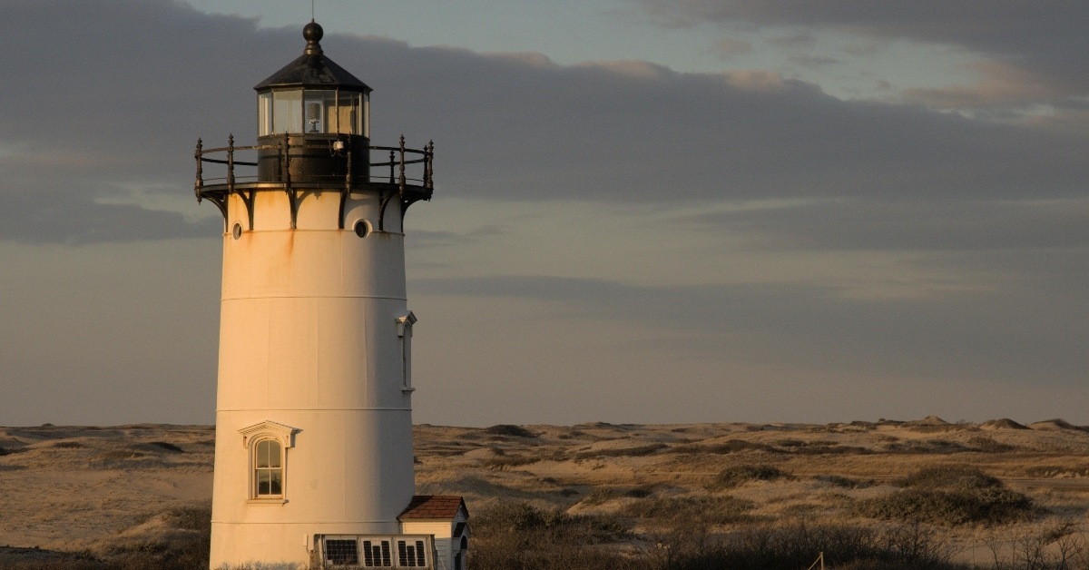 A White Lighthouse on a Grassy Field