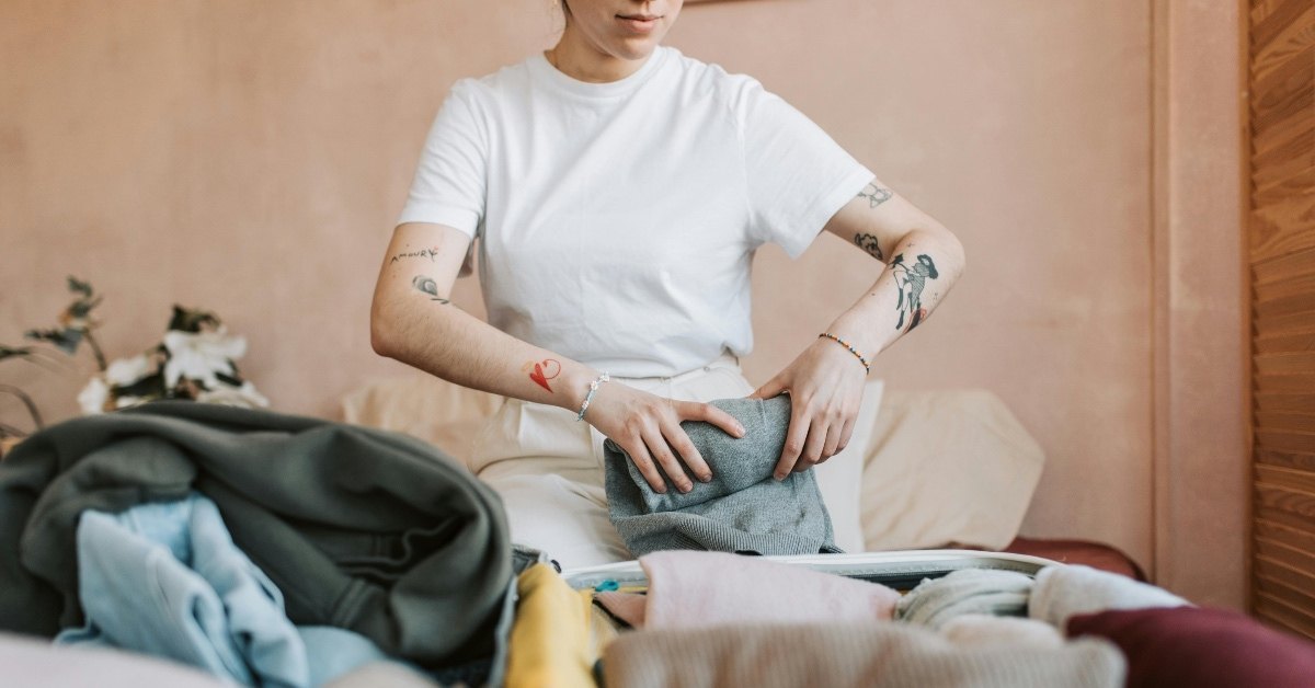 Woman in White T-shirt Folding Her Clothes