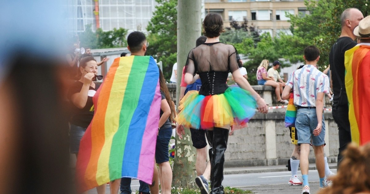 Two people walking in rainbow clothing.