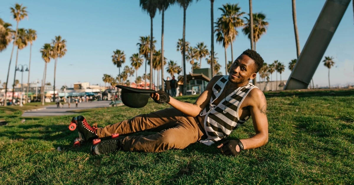 Man in Black and White Stripe Polo Shirt Sitting on Green Grass Field
