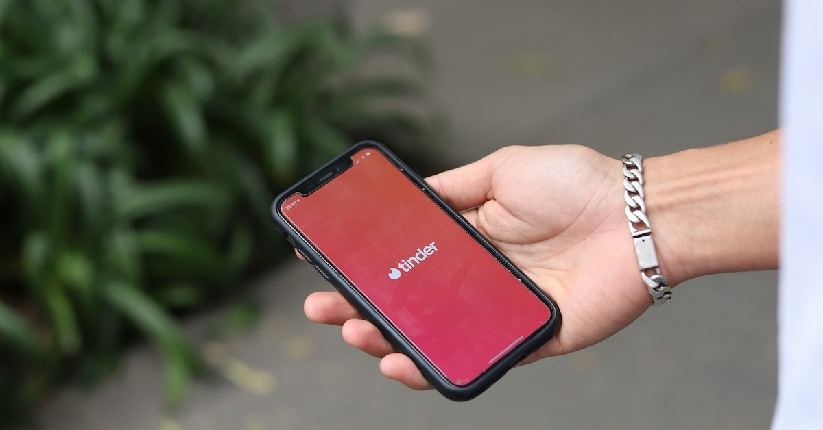 A hand holding a phone that says "Tinder"